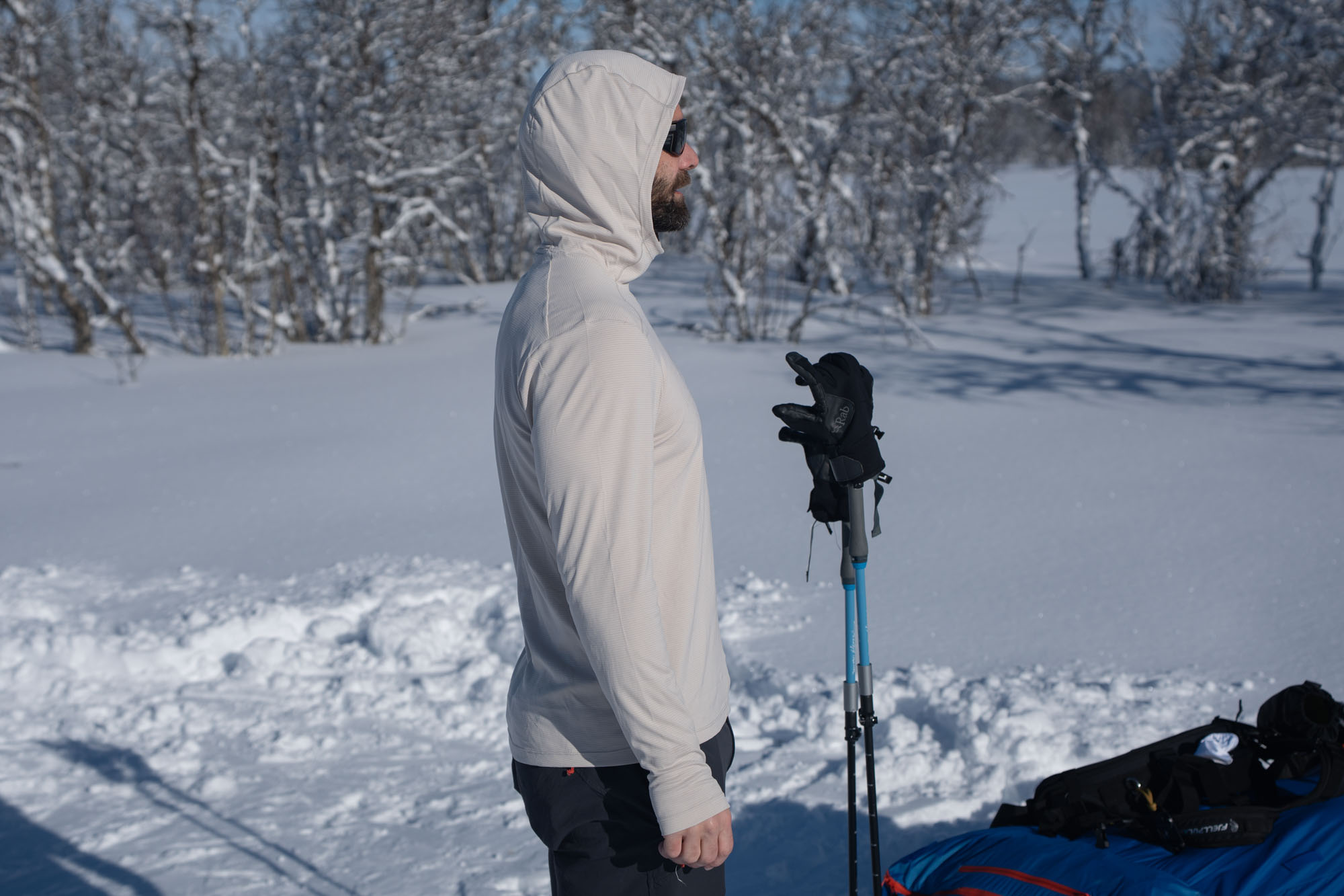 turista v zimní krajině ukazuje profil bílého trika Rab force hoody