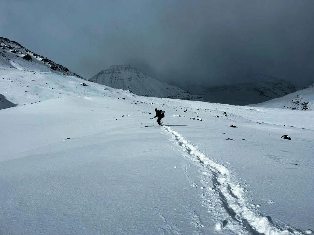 osamělý turisty prošlapává cestu čerstvým sněhem v horách Greater Patagonian Trail